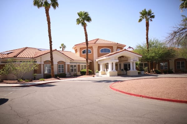 Exterior view of a senior living facility with palm trees
