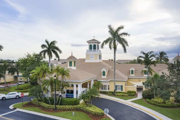 Exterior view of a senior living facility with palm trees