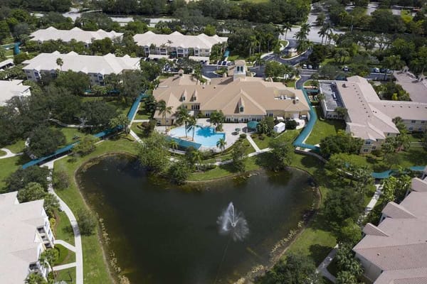 Aerial view of a senior living facility with a lake and pool