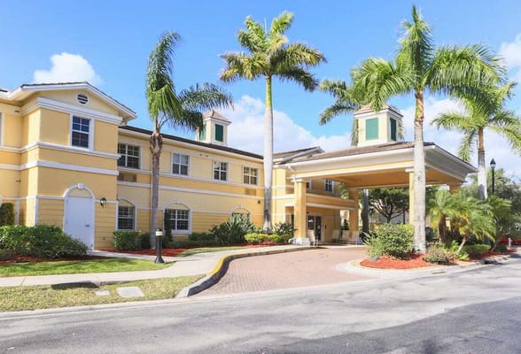 Exterior view of a senior living facility with palm trees