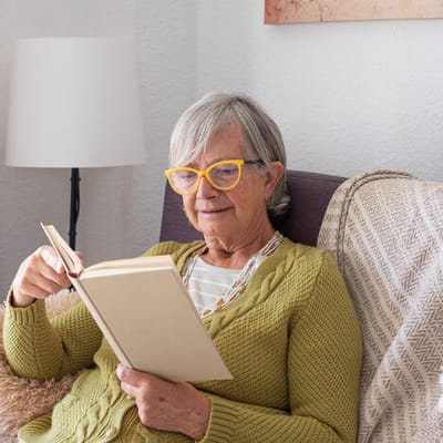 Senior woman reading a book in a cozy chair