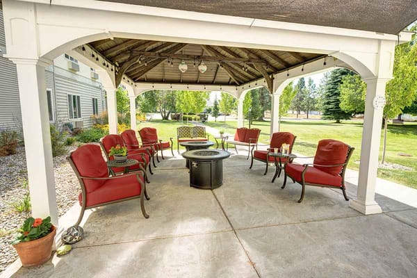 Covered outdoor seating area with red chairs and table