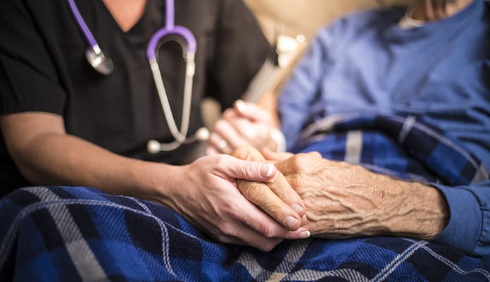 A caregiver holding a resident's hand warmly
