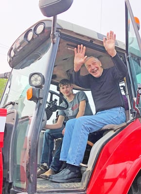 A senior man in a tractor with a young man