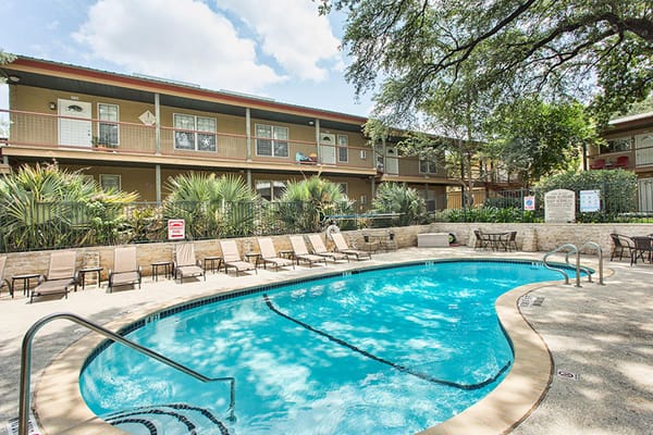 Pool area surrounded by building and lounge chairs