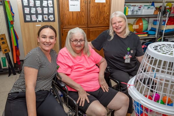 A caregiver and resident smiling together in an activity room
