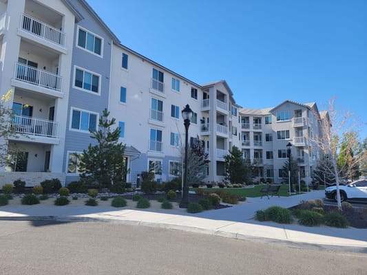 A view of the exterior of Revel Rancharrah senior living facility showcasing balconies and landscaped grounds.