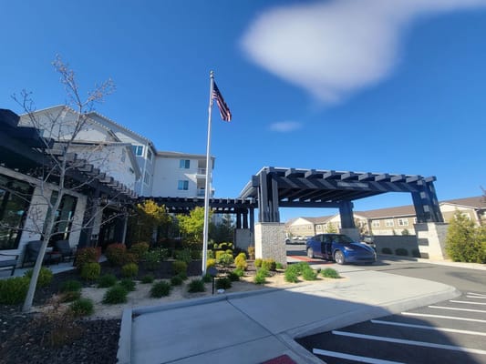 Front entrance of Revel Rancharrah senior living facility with landscaping and flag