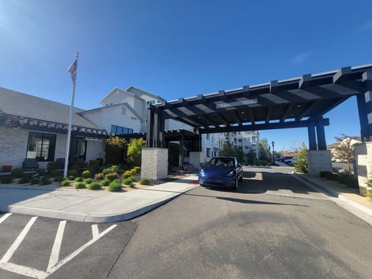 Entrance featuring a covered drive-thru with greenery and an American flag