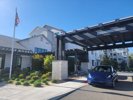 The entrance of Revel Rancharrah senior living facility with a blue car parked under the canopy.