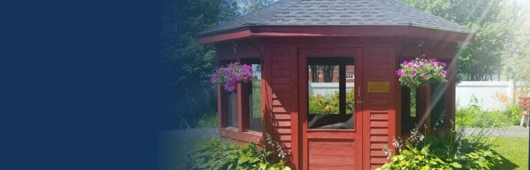 A gazebo with hanging flower baskets in a garden