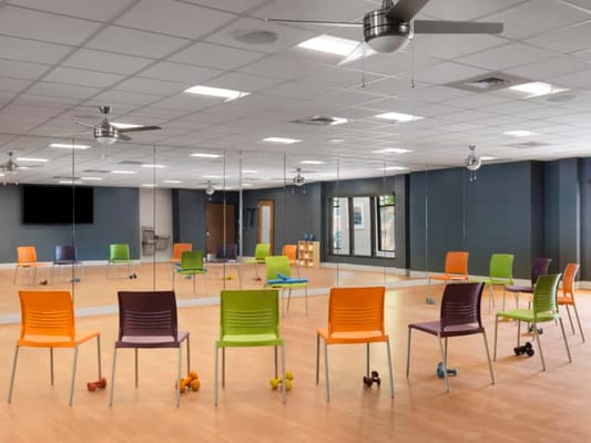 Bright fitness room with colorful chairs and weights