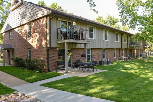 Exterior view of a senior living facility with green lawn and seating areas