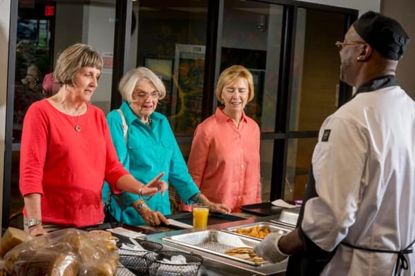 Residents interacting with staff in the dining area