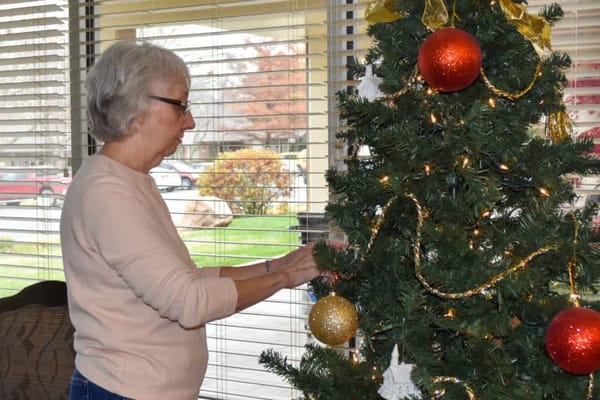 Resident decorating a Christmas tree indoors
