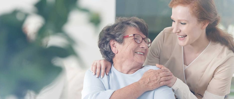 Caregiver smiling with a resident in a bright interior