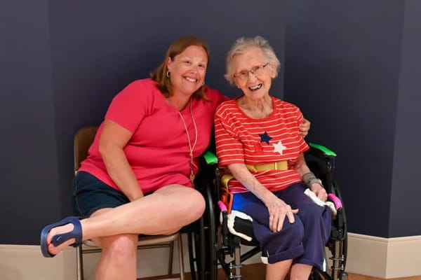 Staff member and resident smiling together in a hallway