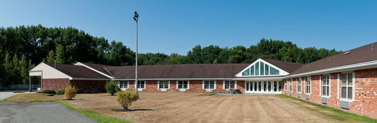 Exterior view of a senior living facility with grass and trees