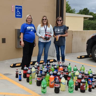 Staff members celebrating with soda bottles in a parking area