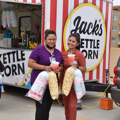 Staff members holding festive food items at an outdoor event