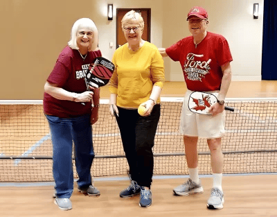 Residents playing pickleball indoors with paddles