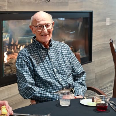 An elderly man smiling at a dining table