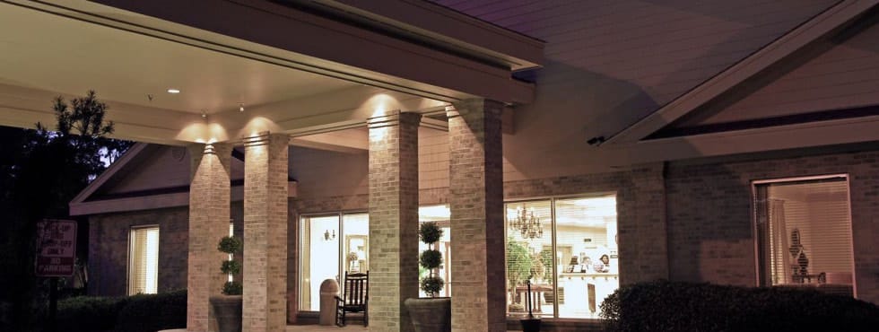 Entrance of a senior living facility with columns and lights