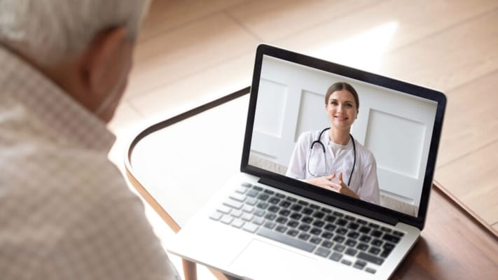 An elderly man using telehealth services on a laptop