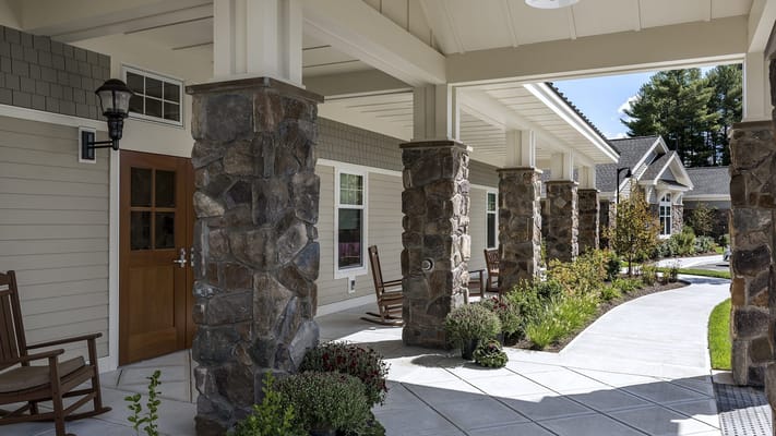 Covered outdoor walkway with rocking chairs and flower beds