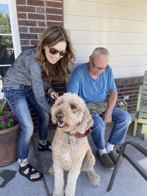 Resident interacting with a caregiver and a dog outdoors