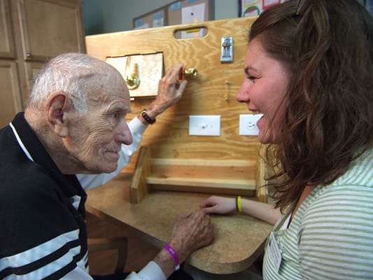 An elderly man engaged with a caregiver in an activity.