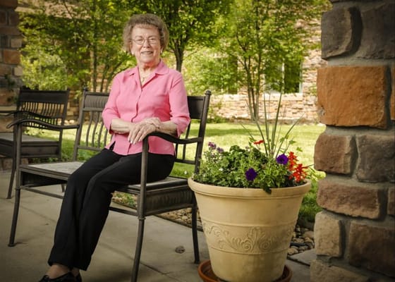Senior resident smiling on a bench in a garden
