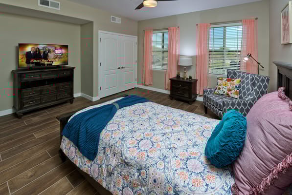 A cozy, well-decorated resident bedroom with a TV
