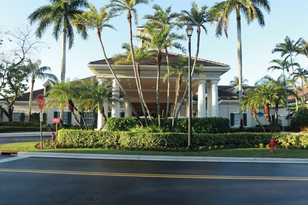 Front entrance of a senior living facility surrounded by palm trees