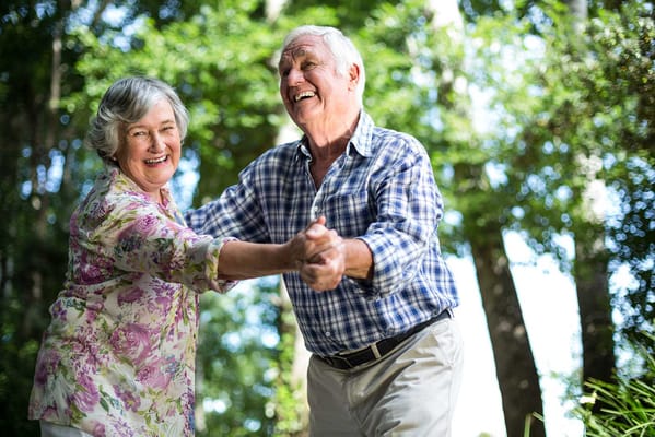 Happy senior couple dancing outdoors in a garden