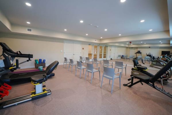 Interior view of a fitness room with equipment and chairs