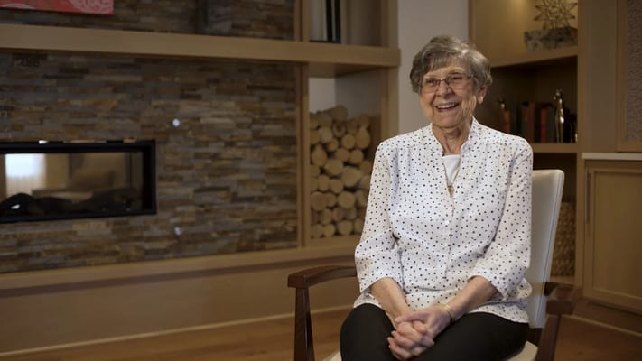 Resident smiling in a well-decorated lounge area