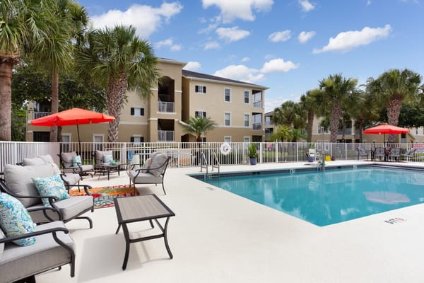 Outdoor pool area with lounge chairs and palm trees