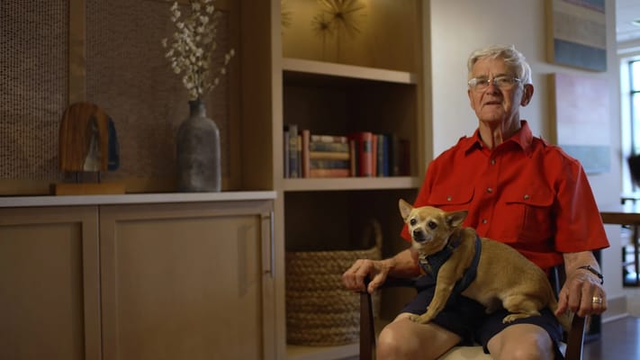 Senior resident sitting with a dog in a comfortable lounge