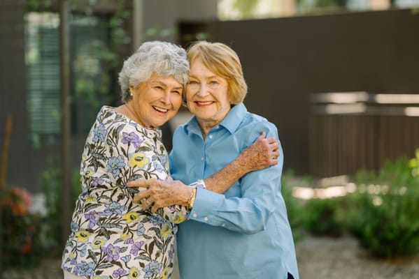 Two residents embracing in a garden area