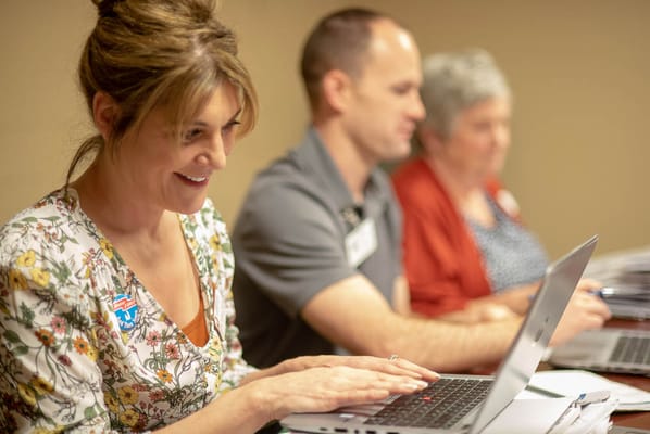 Staff members working on laptops in an activity room
