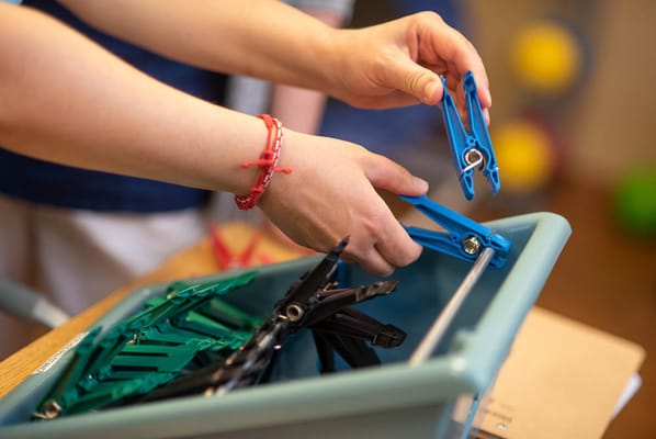Hands organizing colorful clothespins in a box