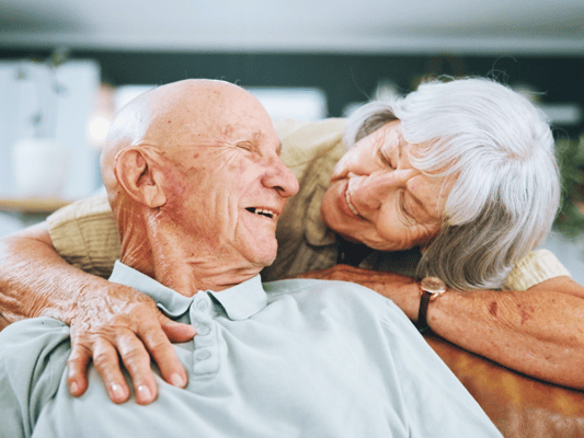 An elderly man and woman sharing a joyful moment indoors