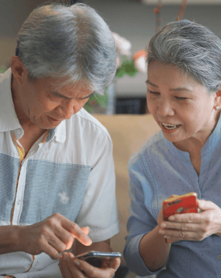 Two seniors engaged with their smartphones in a common area