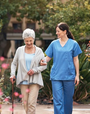 A caregiver assisting a senior woman outdoors