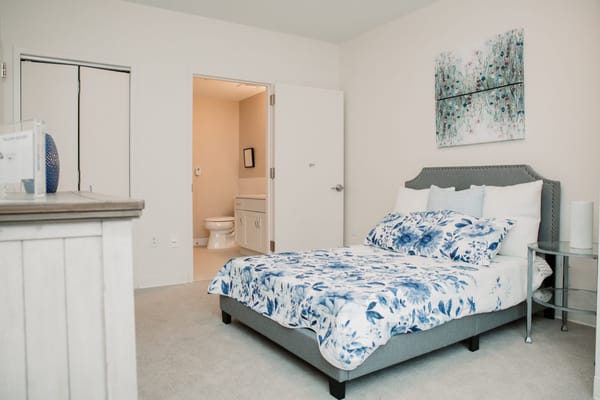 A bright, furnished resident room with floral bedding