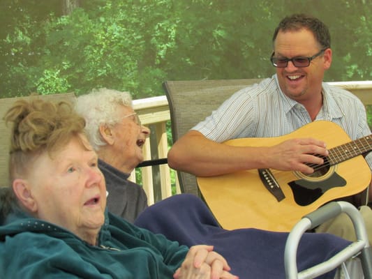 Residents enjoying live music outdoors with a musician