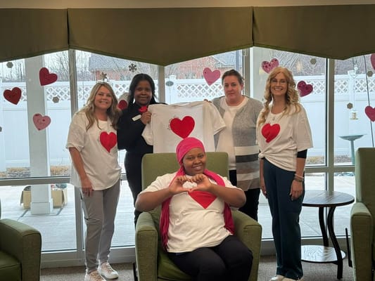 Staff and residents celebrating with heart shirts in a common area