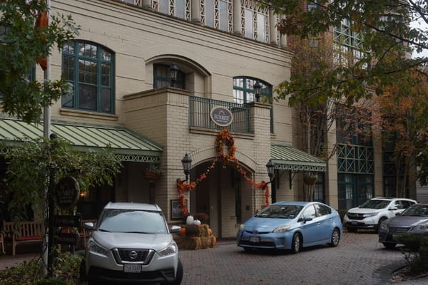 The entrance of Sunrise of Connecticut Avenue with autumn decorations and parked cars.