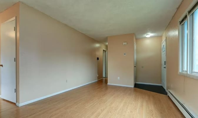 Empty interior room with light-colored walls and wooden floor